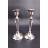 A pair of George V silver candlesticks, each having bell-form socket, tapering stem and cavetto-