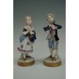 A pair of European porcelain figurines modelled as a boy and girl in 18th Century style costume,