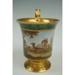 A 19th Century Berlin porcelain cup, hand-enamelled in depiction of deer amongst woodland, (a/f), 11