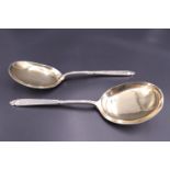 A pair of late Victorian silver serving spoons, each having Romanesque relief-moulded terminal and