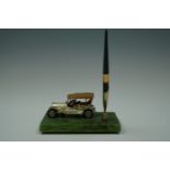 A 1960s kitsch pen and desk stand modelled as a veteran car on a faux onyx base