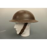 A Second World War steel helmet, retaining its original factory-applied gloss tan paint finish and