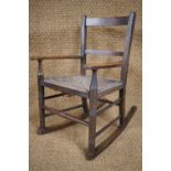 An early 20th Century child's rush-seated rocking chair, 66 cm