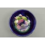 A William Moorcroft footed bowl, of circular section, decorated with a pansy over a cobalt blue