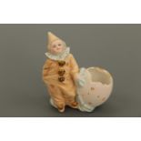 A late 19th Century novelty bisque porcelain figural spill vase modelled as a child in a Pierrot