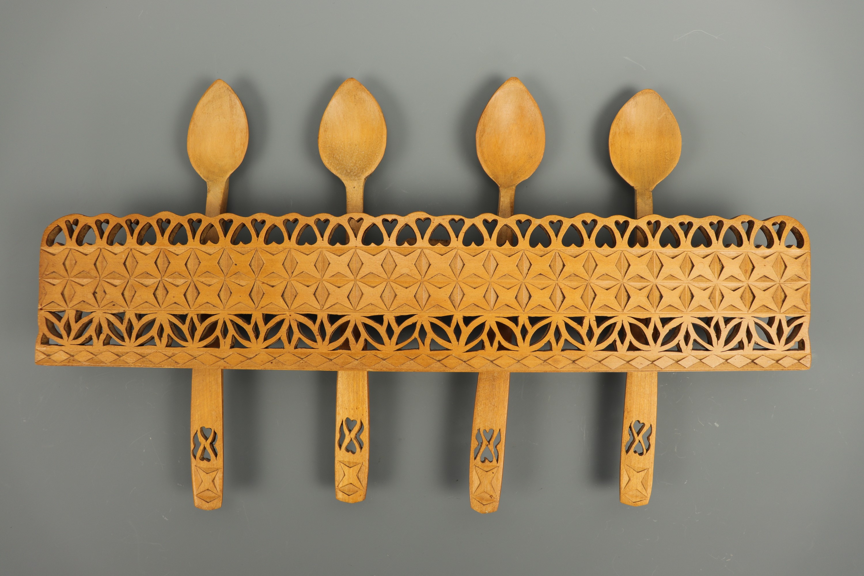 A Welsh chip-carved wooden rack and spoons, spoons 26 cm long