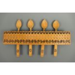 A Welsh chip-carved wooden rack and spoons, spoons 26 cm long