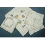 A quantity of hand-embroidered tea table and tray cloths, worked in colourful cotton threads over
