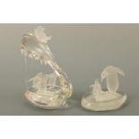 Two contemporary part-frosted glass sculptures of penguins, one depicting the birds playfully