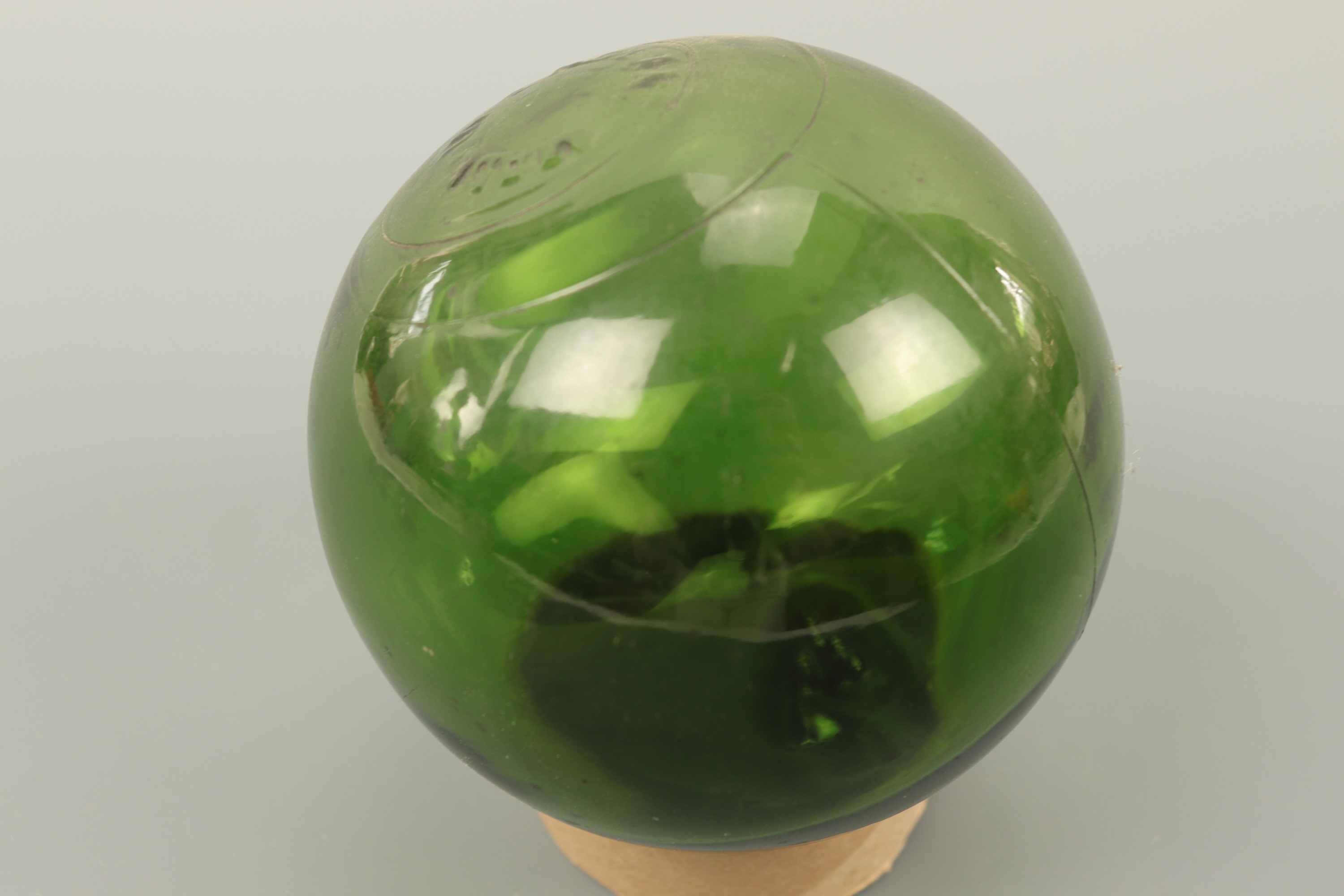 A vintage blown green glass fishing float, approximately 13 cm