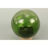 A vintage blown green glass fishing float, approximately 13 cm