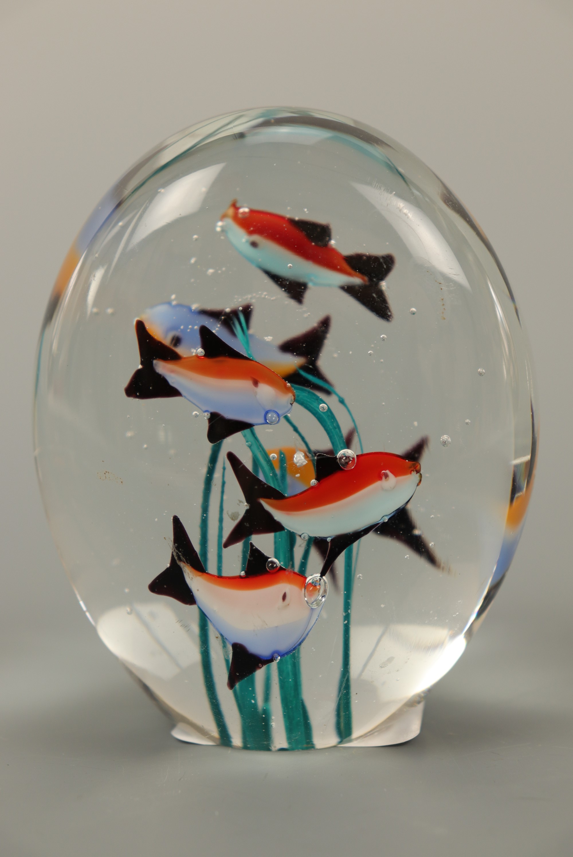 A vintage kitsch glass paperweight depicting fish surrounding seaweed, 10 cm