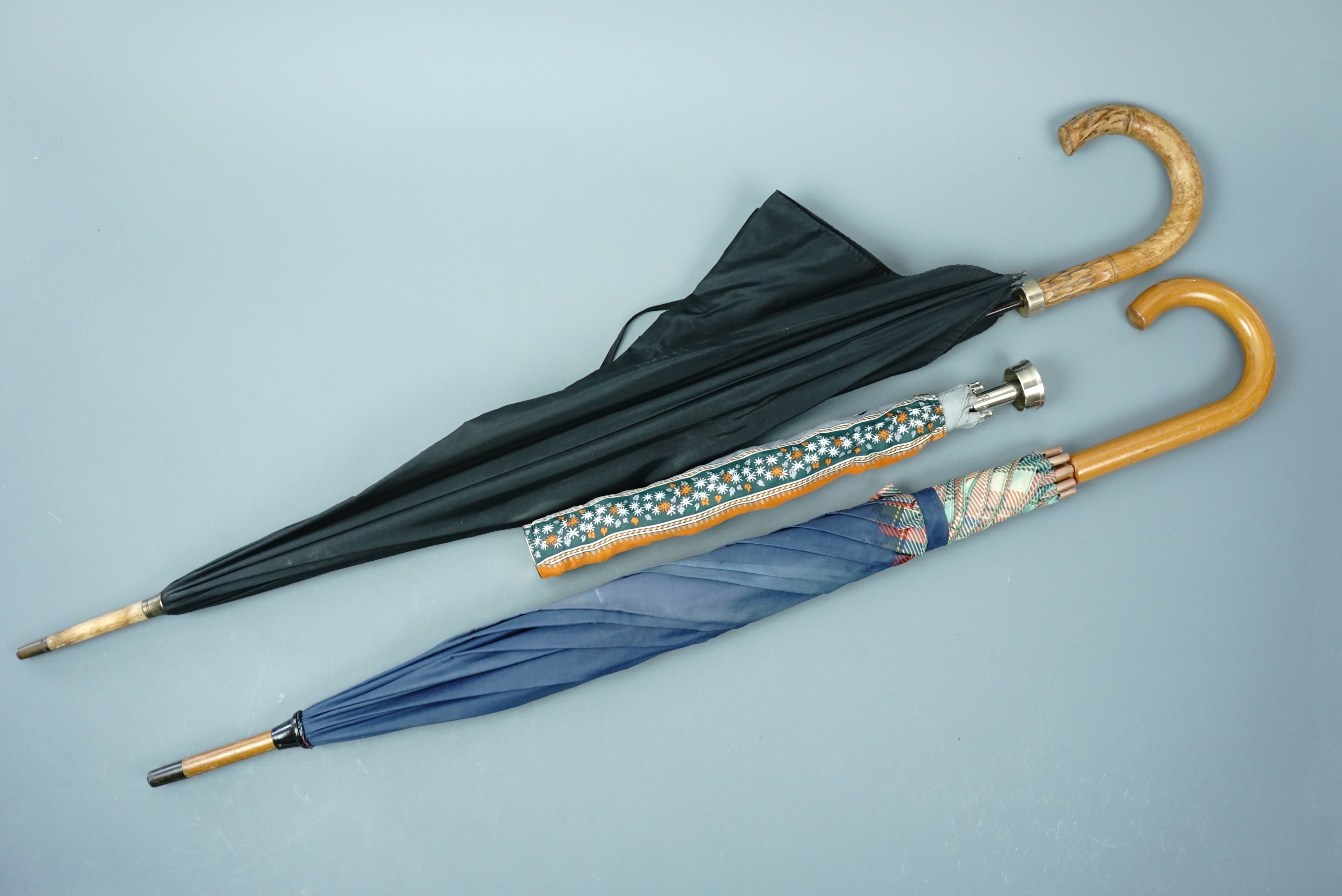 Three vintage umbrellas, two having cane handles, the third of compact design