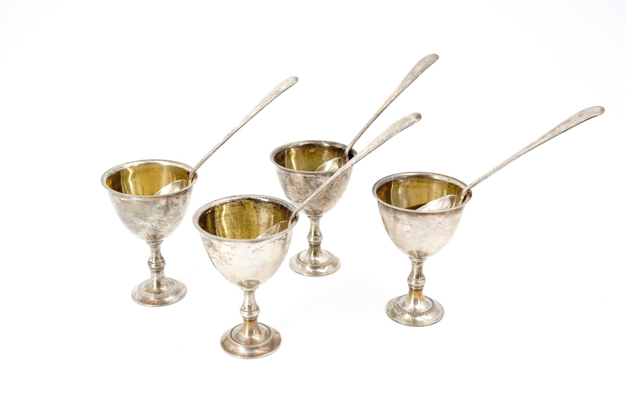 A vintage set of four parcel-gilt and electroplate egg cups and spoons