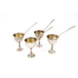 A vintage set of four parcel-gilt and electroplate egg cups and spoons