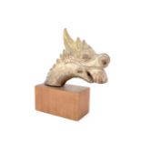 An antique Asian carved wood beast's head, decorated with gesso, ochre and green paint, on a
