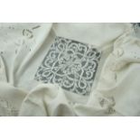 An antique linen table cloth, decorated with cutwork embroidered floral bouquets and lace inserts,