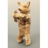 A naive agate glazed terracotta model of a pig holding a rodent, the pig modelled in a kneeling