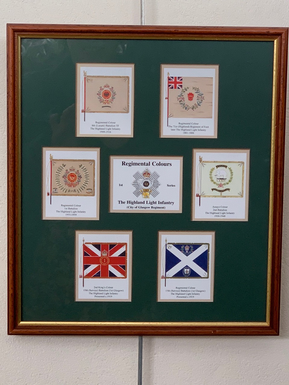 A Framed display of cards depicting the regimental colours of the Highland Light Infantry, 33 cm x