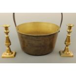 A brass jam pan, 34 cm diameter, together with a pair of brass candlesticks 22 cm high