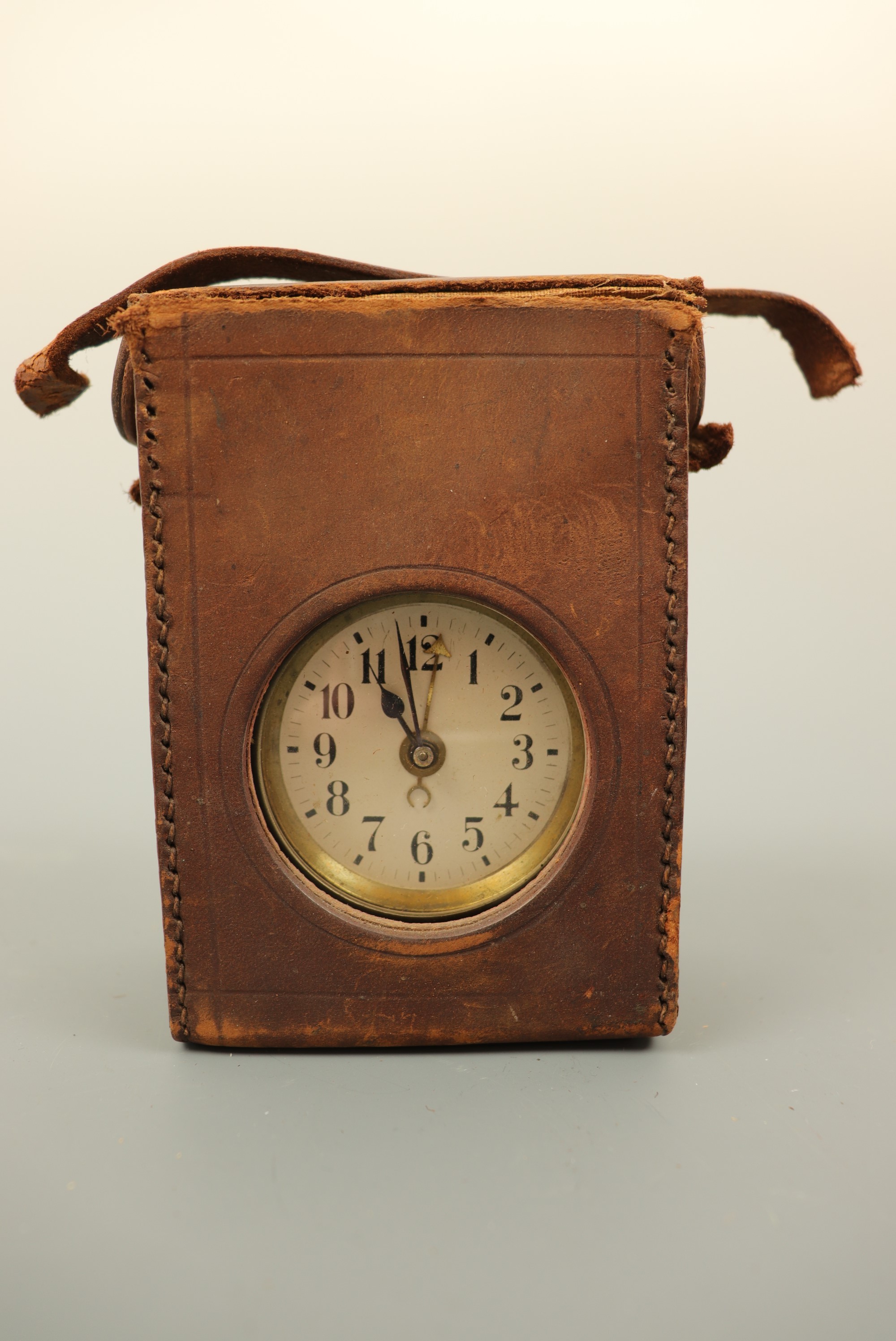 An early 20th Century bedside travel alarm clock, with silvered dial and Arabic numerals, in a