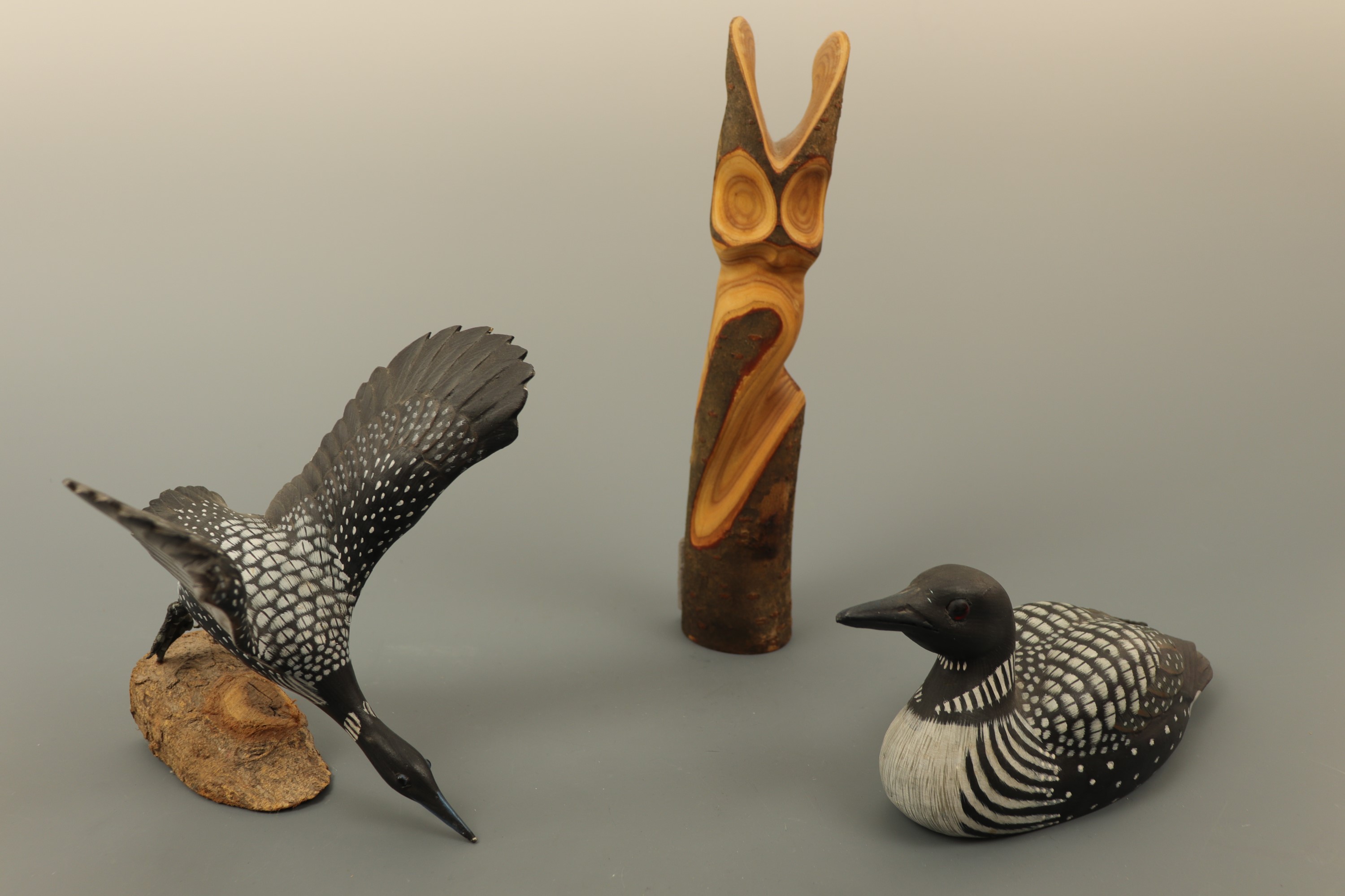 Two hand carved and painted wooden bird figures, together with a carved stylized long eared owl