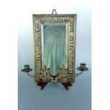 An antique brass framed two-branch candle sconce, bearing repousse decoration in the form of fruit