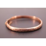 A Victorian 9ct rose gold hinged bangle, the face bearing engraved scrolling foliate decoration, 7.