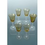 Six mid-20th Century wine glasses, each having a finely reeded amber glass bowl and multi-knopped