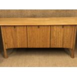 An Ercol Saville pattern elm sideboard with integral drinks cabinet, having a shaped plank top, over