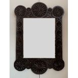 An oak framed wall mirror with chip carved decoration incorporating flower head motifs, 63 x 90 cm