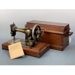 An antique Singer sewing machine, hand-driven, in wooden case together with Singer instruction