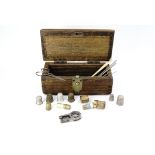 An antique wooden box containing a quantity of sewing tools, including two silver thimbles, and a