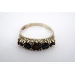 A 9ct gold and five stone garnet ring, claw and pellet-set above a scrolling gallery, size M, 2.4 g