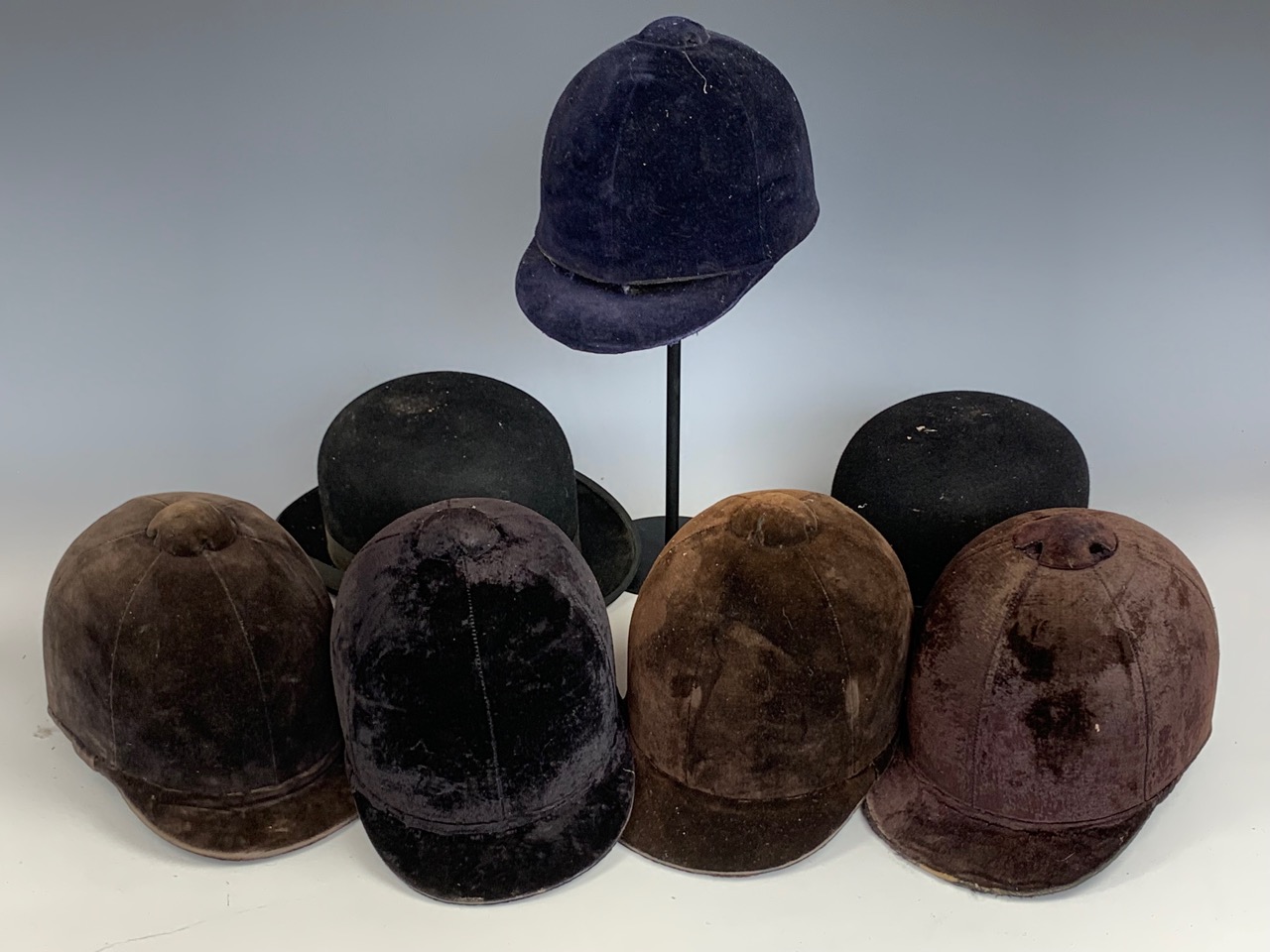 A group of vintage riding helmets and hats