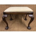 A George V upholstered mahogany stool, having a drop-in seat, cabriole legs and ball-and-claw feet