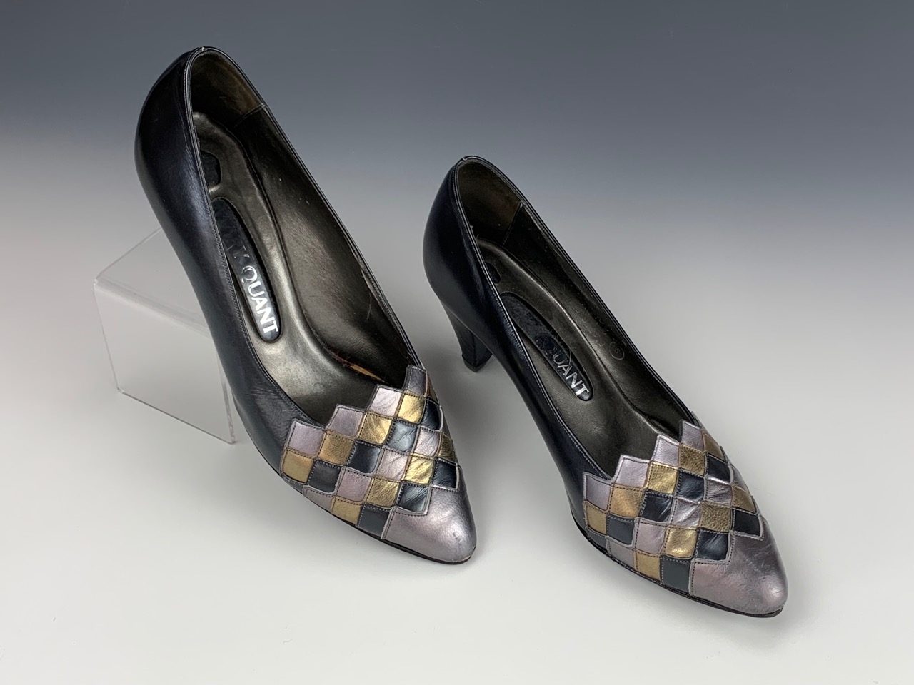 A 1980s pair of Mary Quant court shoes, in navy blue with a metallic diaper pattern toe,