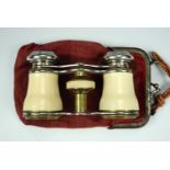 An antique pair of brass opera glasses, in a red velvet finger purse