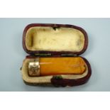 An early 20th Century gold-collared amber cheroot holder, cased
