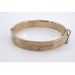 An Edwardian 9 ct gold hinged bangle, engraved in cursive script with the name Margaret May, 11.4 g