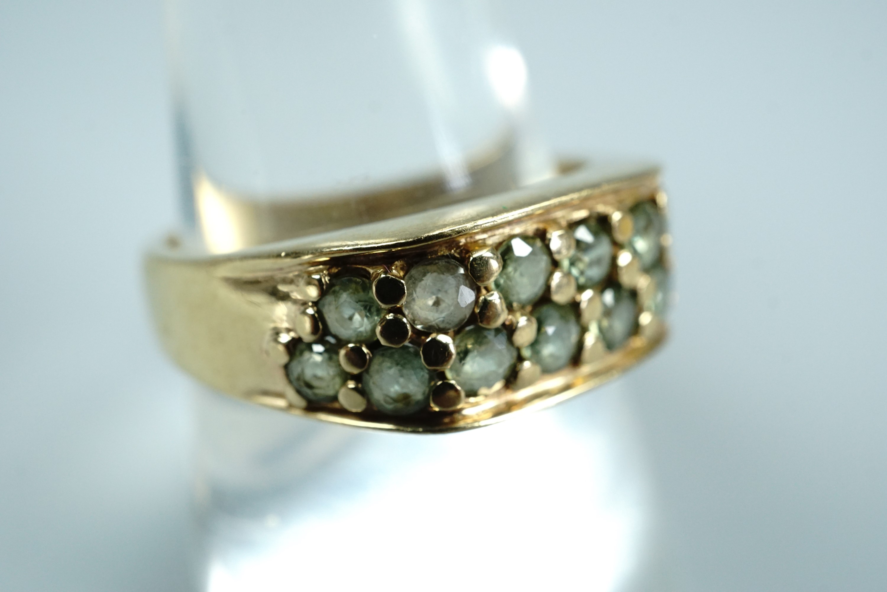 A contemporary 9ct gold and green sapphire statement ring, having two rows of pellet-set round-cut
