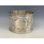 A Chinese white-metal napkin ring, decorated in the round with figures on a busy river, with