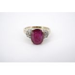 A contemporary 9ct gold ruby and diamond cocktail ring, having a central oval-cut ruby of