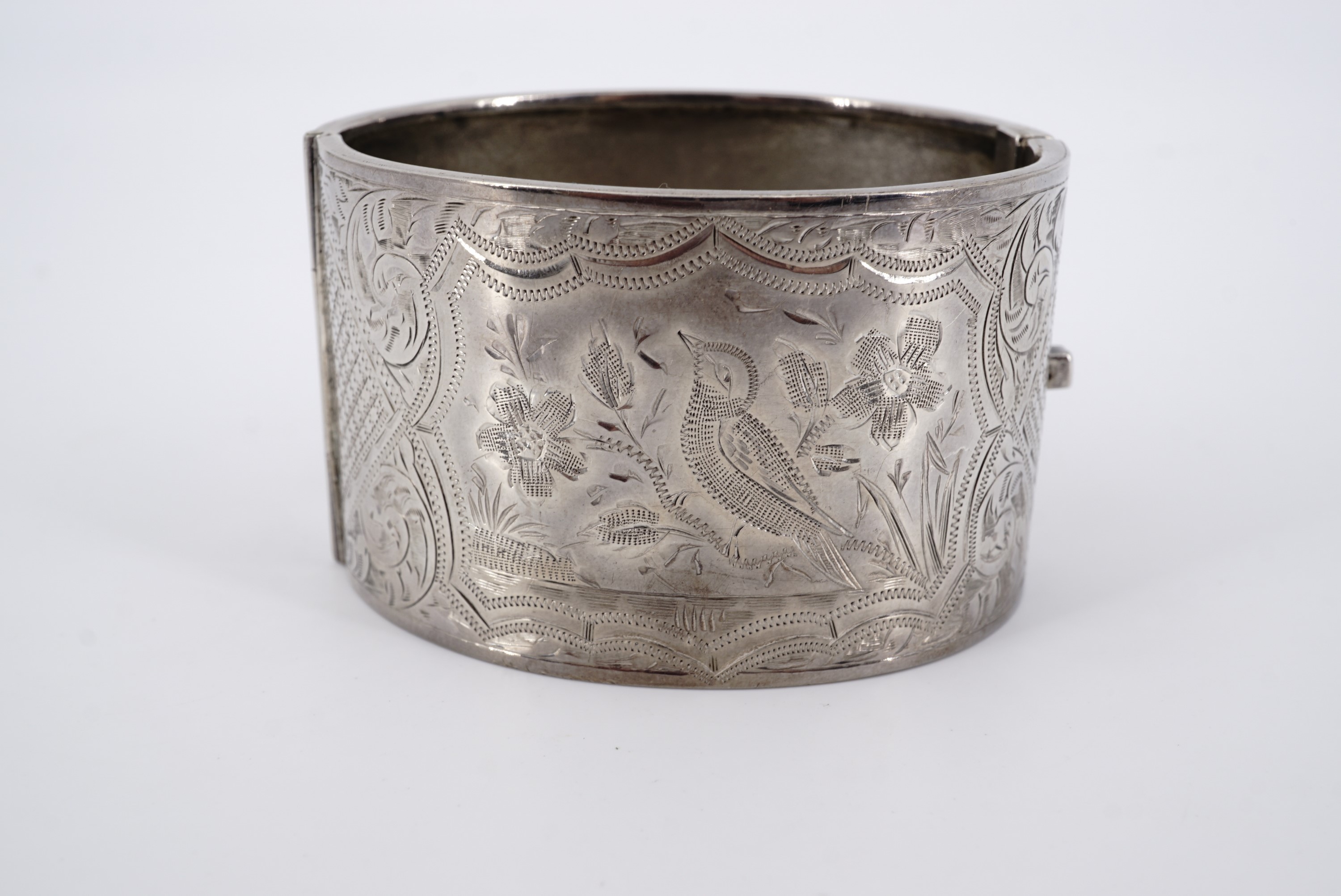 A George V silver hinged cuff bangle, the face wriggle-work and bright-cut engraved with a song bird