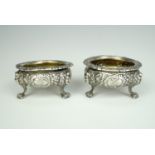 A pair of 18th / early 19th Century silver salt cellars, profusely floral relief decorated,