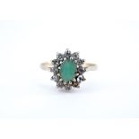 An emerald and diamond flowerhead cluster ring, set with an oval emerald of approx. 0.4 ct, on a 9