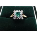 A contemporary 18ct gold, emerald and diamond dress ring, having a central round-cut emerald of