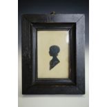 An early 19th Century silhouette of a young girl, her short hair curling at the nape of her neck,