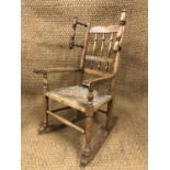 A Victorian child's rush seated spindle back rocking armchair, 79 cm