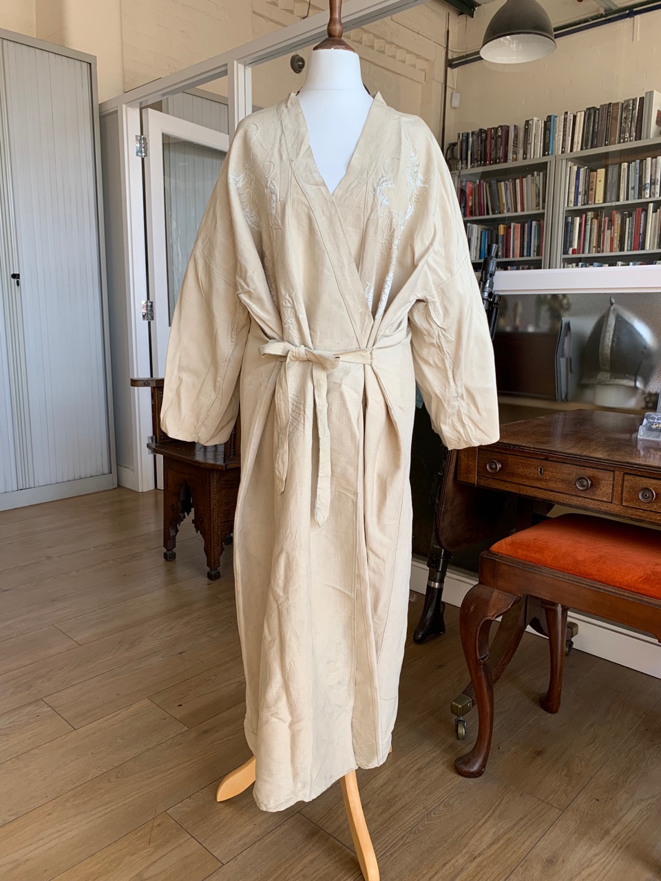 A 1930s Chinese robe or lady's house coat, the natural ground silk embroidered in depiction of
